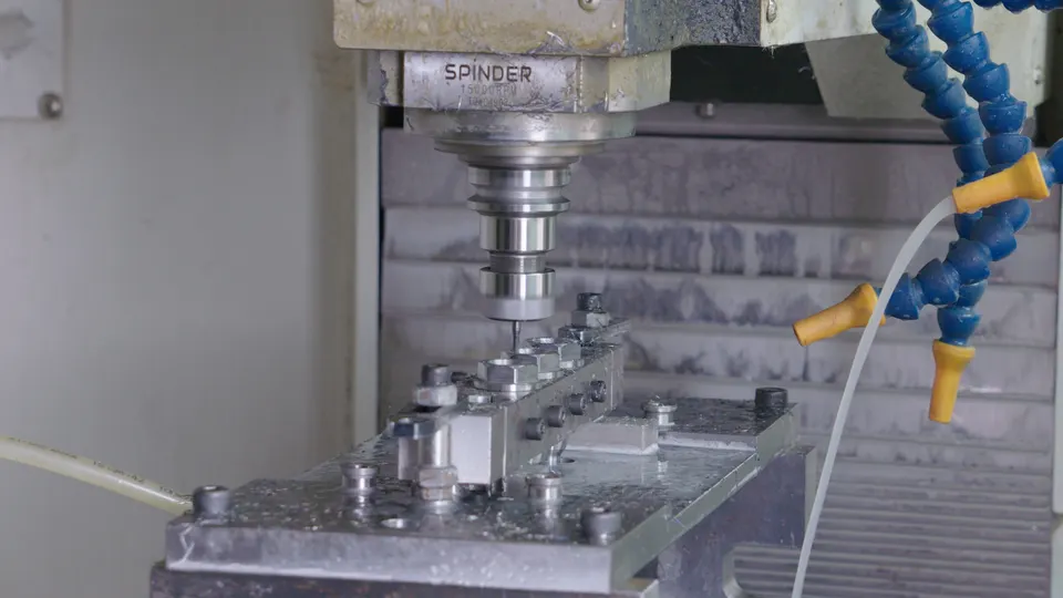 CNC spindle milling a metal workpiece with coolant lines in view