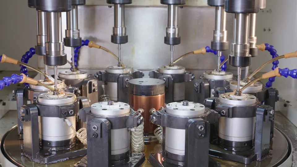 Circular multi-spindle machining setup with coolant lines and workholding stations